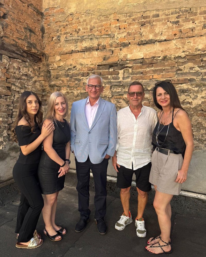 Patrick Kukuck mit einem Salonteam vor einer alten Backsteinmauer